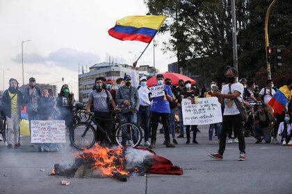 Manifestantes cerca de objetos en llamas mientras protestan contra la pobreza, la violencia policial y las desigualdades de los sistemas de salud y educación, en Bogotá, Colombia (Reuters)