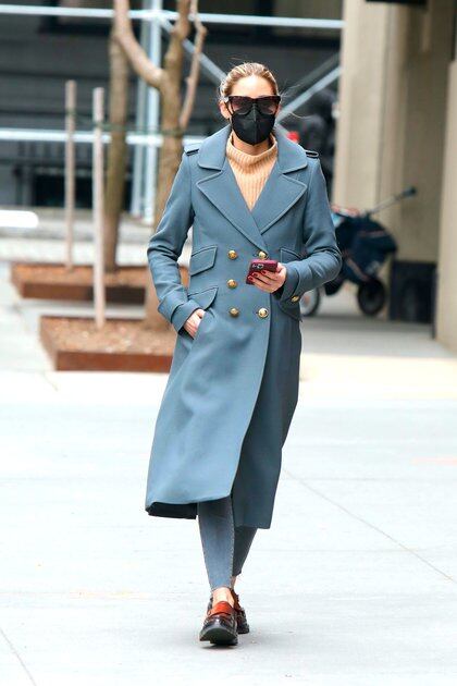 Olivia Palermo dio un paseo por las calles de Dumbo, en Brooklyn, Nueva York. Lució unas calzas y tapado azul con botones dorados, una polera marrón, lentes de sol y tapabocas negro
