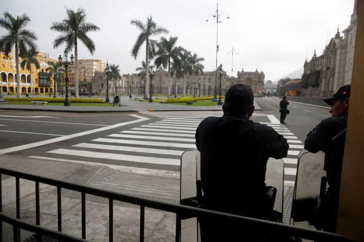 Oficiales de policía vigilan la vacía Plaza de Armas de Lima después de que el gobierno de Perú desplegara personal militar para bloquear las principales calles en medio de un estado de emergencia de 15 días para frenar la propagación del coronavirus (REUTERS/Sebastian Castañeda)