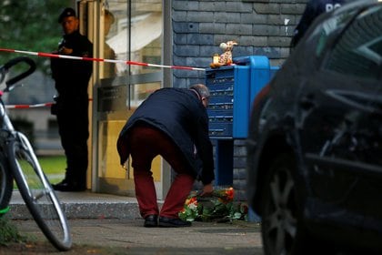 Un hombre deposita flores a la entrada del bloque de apartamentos de la tragedia. 