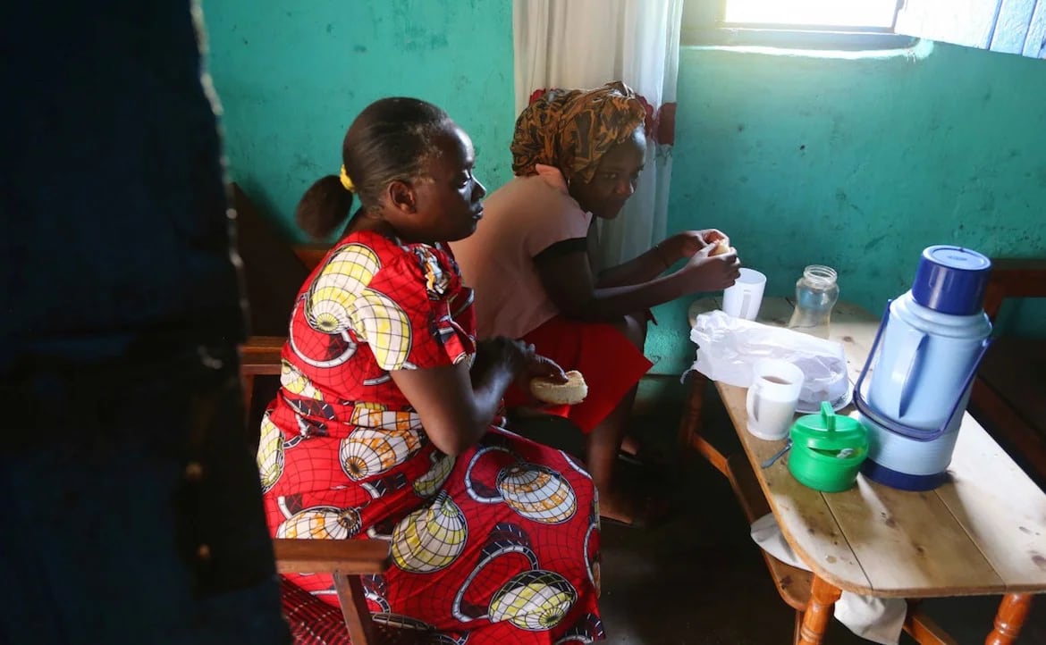 Angel toma té y come pan junto a su madre Jacqueline, en la casa que ambas comparten en Ruanda. (Whitney Shefte)