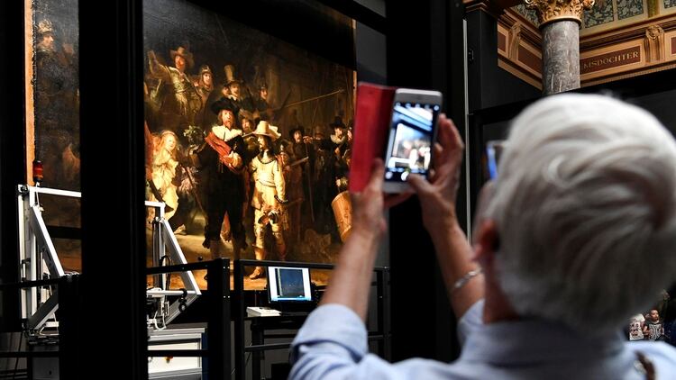 Una mujer fotografía la obra de Rembrandt, protegida por una barrera de vidrio y cámaras de video. (Foto: REUTERS)