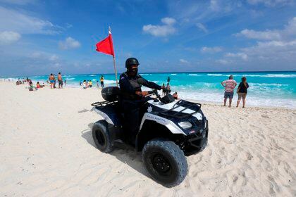 Un policía patrulla una playa con algunos turistas en Cancún (Foto: EFE/Alonso Cupul)
