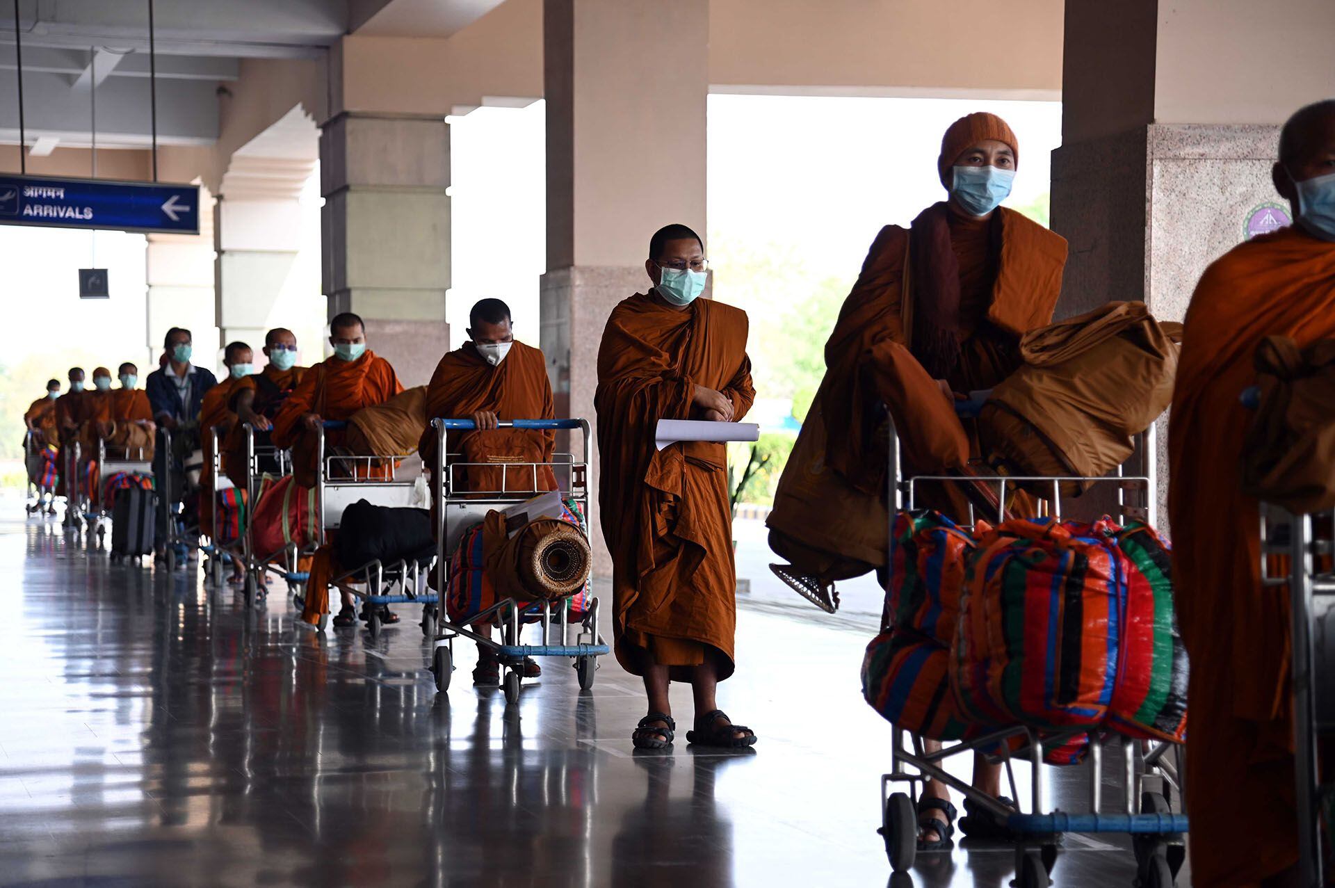 Monjes budistas de nacionalidad tailandesa hacen cola antes de facturar un vuelo con destino a Tailandia durante la cuarentena en el aeropuerto internacional de Gaya, a unos 5 km de Bodhgaya, el 24 de abril de 2020. (Foto de SUMAN / AFP)