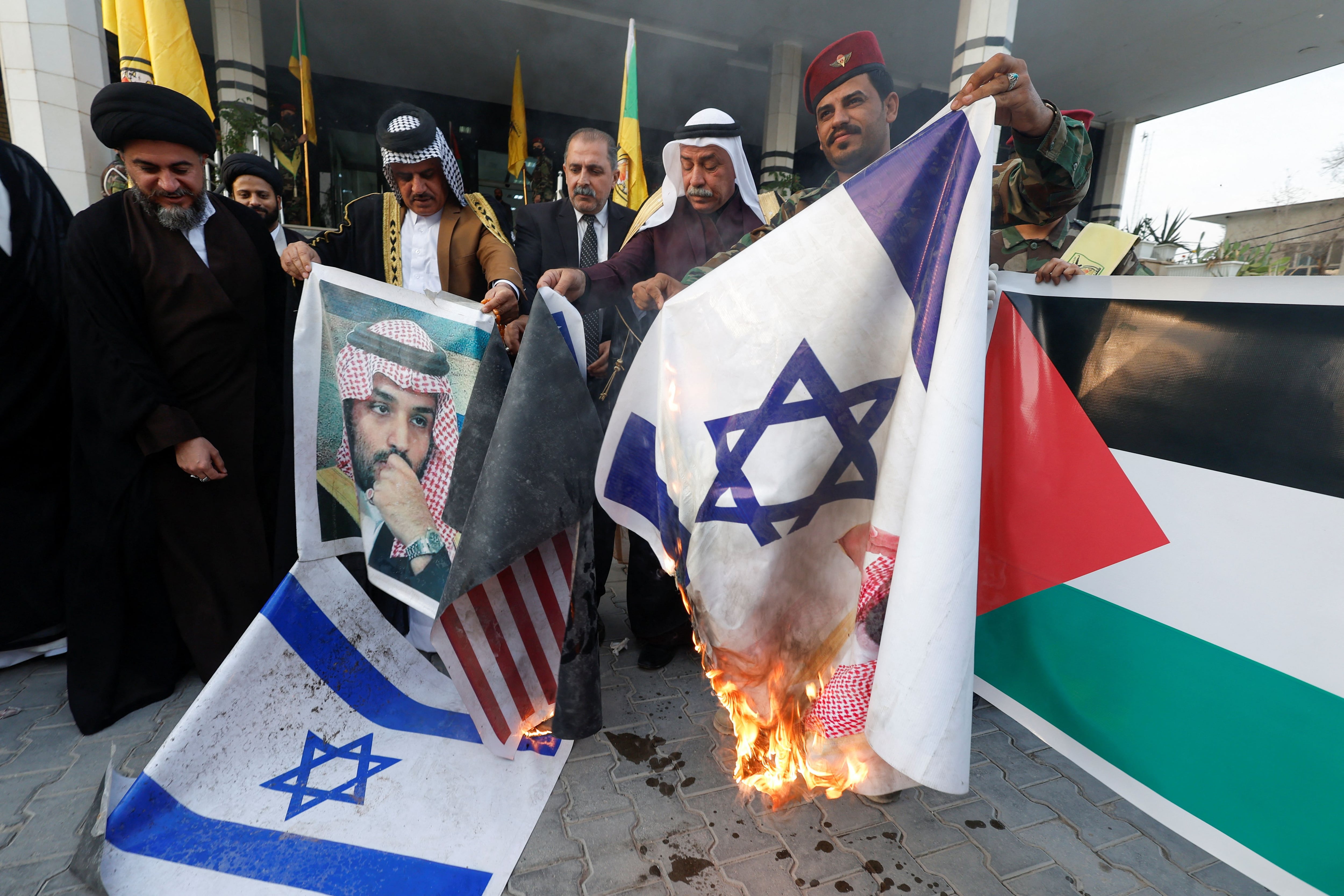 Un miembro de Kataib Hezbolá junto a otros hombres queman banderas nacionales de Estados Unidos e Israel y una foto del príncipe heredero saudí Mohammed bin Salman durante una protesta en solidaridad con los palestinos de Gaza, en Nayaf, Irak, 11 de octubre de 2023. REUTERS/Alaa al-Marjani