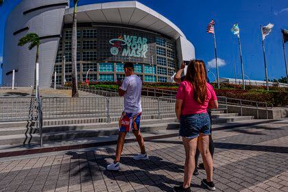 Some people take photos of a banner with the Miami Heat emblem and a slogan that says "Wear your mask" hanging on the facade of the American Airlines Arena in Miami, Florida (USA). EFE / Giorgio Viera / Archive