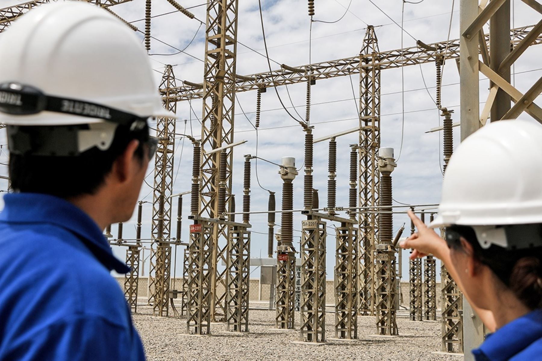 Dos ingenieros supervisan una subestación de distribución de energía eléctrica.