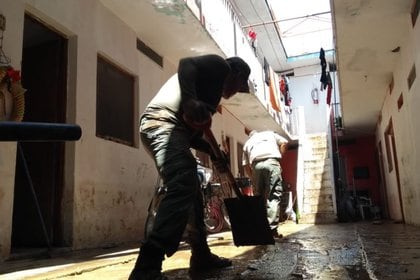 Un elemento de Protección Civil ayuda a limpiar una casa cubierta de barro en San Patricio Melaque (Foto: Twitter Protección Civil de Jalisco)