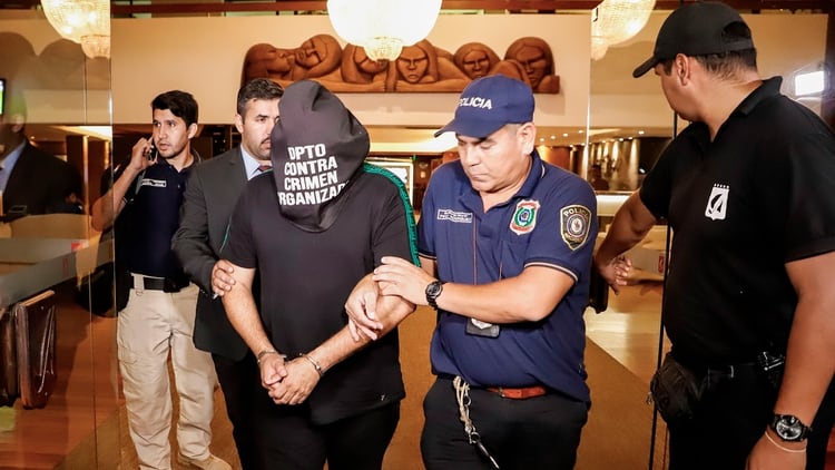 El ciudadano brasileño Wilmondes Sousa, de 45 años, sale arrestado del Hotel Yacht y Golf Club, donde Ronaldinho paso la noche bajo custodia policial (EFE)