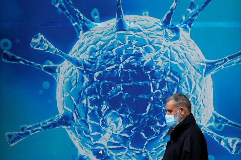 IMAGEN DE ARCHIVO. Un hombre utilizando una mascarilla camina cerca de una ilustración de un virus fuera  de un centro regional de ciencia en Oldham, Gran Bretaña. Agosto 3, 2020. REUTERS/Phil Noble