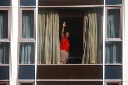 Una mujer saluda desde una habitación del hotel Radisson Blu Hotel en el Aeropuerto Heathrow de Londres (Reuters)