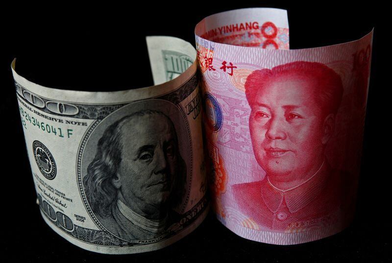 FOTO DE ARCHIVO: Un billete de 100 yuanes junto a un billete de 100 dólares. REUTERS/Petar Kujundzic