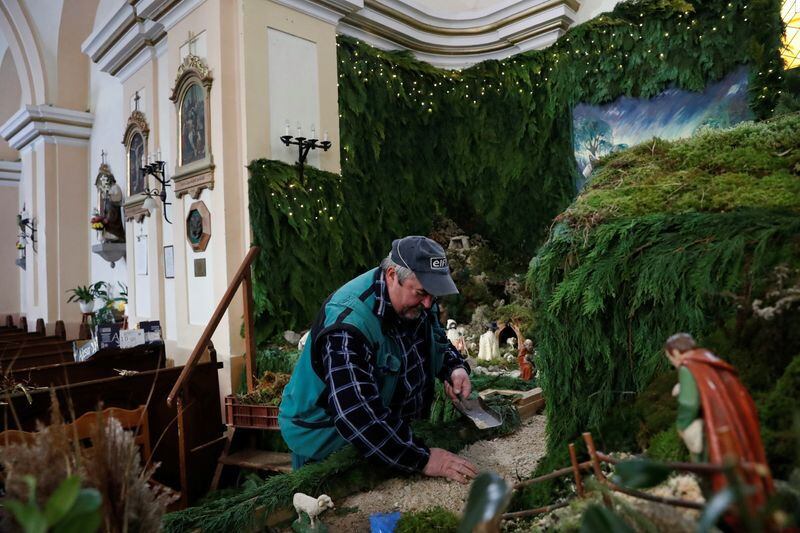 Un hombre trabaja en el montaje de un pesebre navideño en la iglesia de San Martín, Vors, Hungría, 25 noviembre 2021.REUTERS/Bernadett Szabo