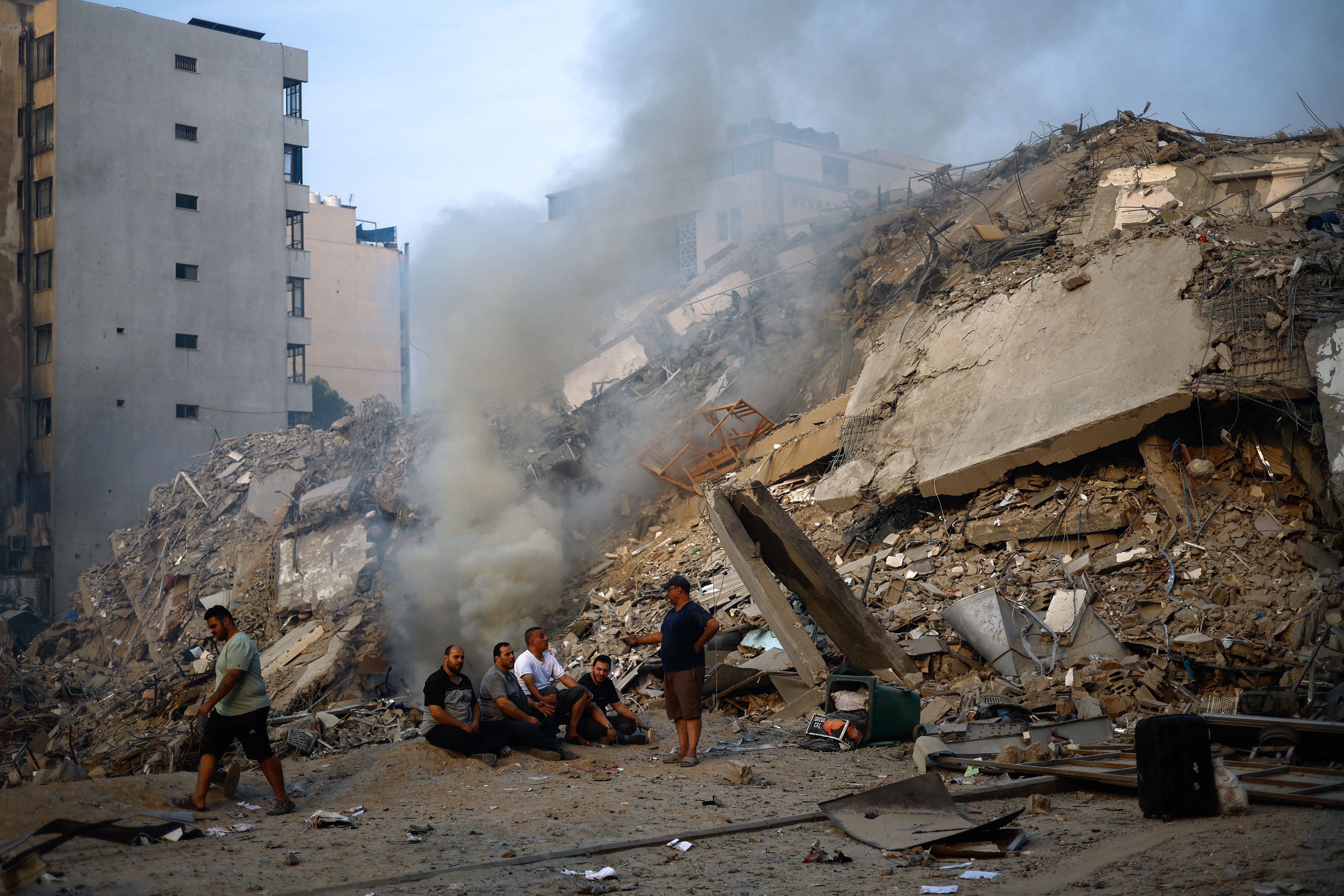 Palestinos se reúnen junto a las ruinas de la torre Watan, donde Hamas tenía oficinas, destruida en ataques israelíes, en la ciudad de Gaza el 8 de octubre de 2023 (Reuters)