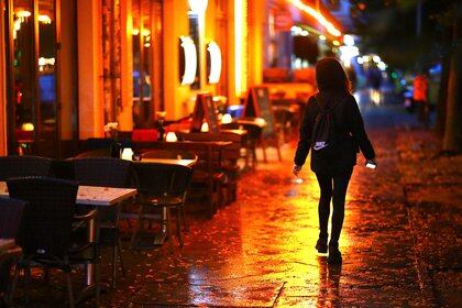 A woman passes empty tables before the late-night curfew due to restrictions against the spread of the coronavirus disease (COVID-19), as city-wide bars and restaurants have to close at 11pm (2100 GMT) until 6am (0400 GMT), in Berlin, Germany, October 14, 2020. REUTERS/Hannibal Hanschke