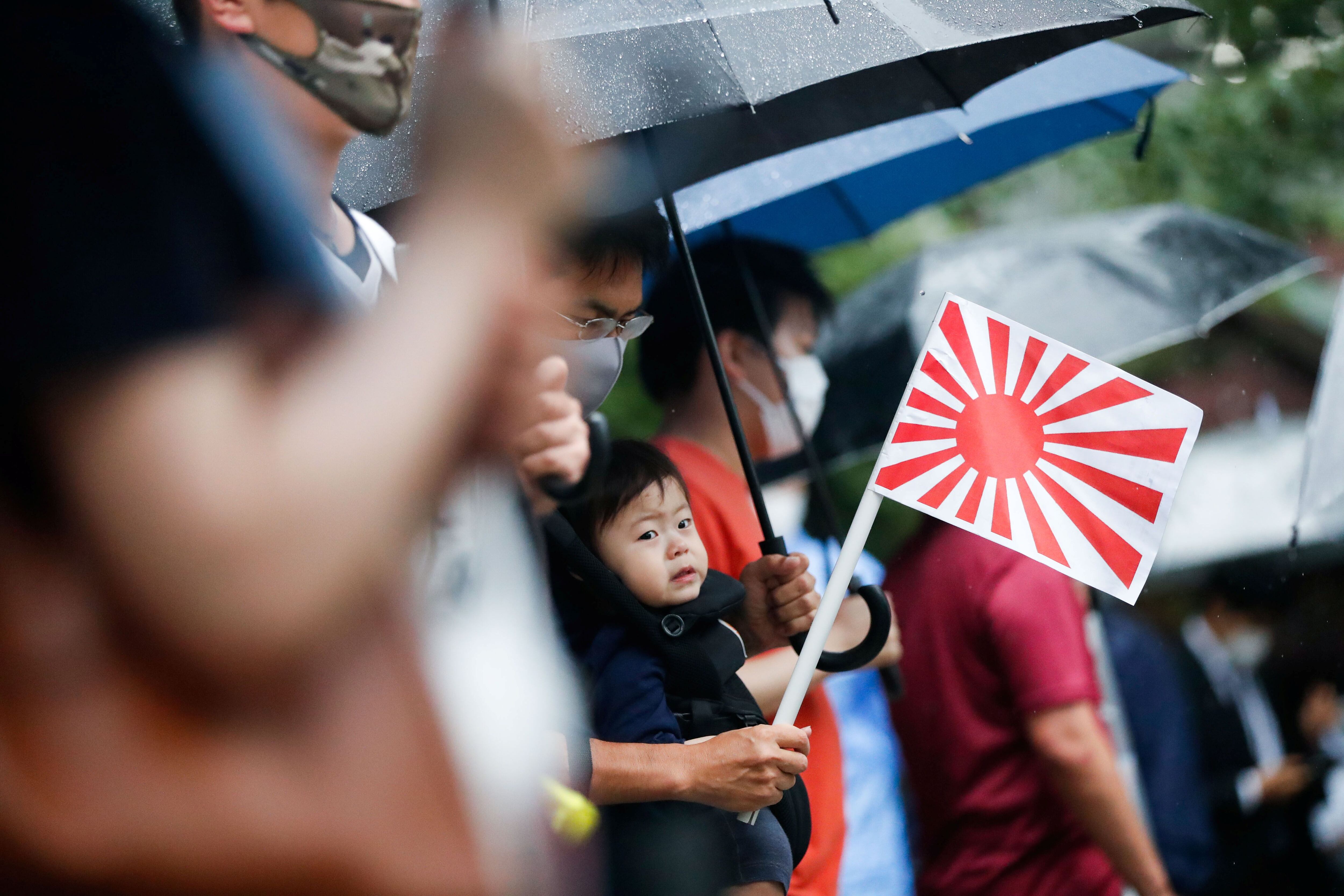 Un padre sostiene una bandera del sol naciente lleva a su hijo durante una visita al Santuario Yasukuni en Tokio, Japón (REUTERS/ issei kato)