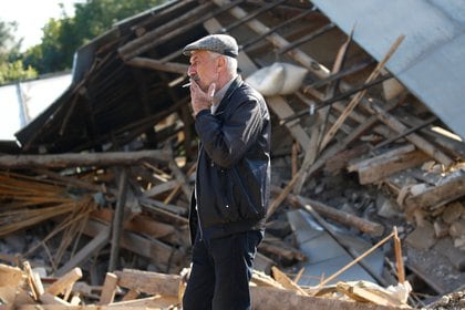 Un hombre fuma ante un edificio derrumbado por bombardeo en la región de Nagorno-Karabakh. REUTERS/Stringer