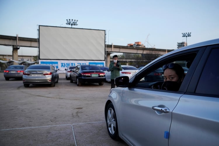 Una mujer se prepara para ver una película desde su auto en un autocine que se ha hecho temporalmente para que los residentes disfruten de las películas mientras mantienen el distanciamiento social en Seúl, Corea del Sur, el 27 de marzo de 2020 (REUTERS/Kim Hong-Ji)