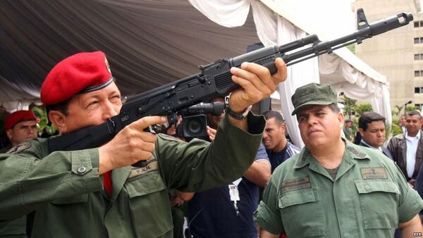 Hugo Chávez manipulando un fusil de asalto Kalashnikov AK-103 bajo la atenta mirada del entonces ministro de Defensa, Orlando Maniglia, el 14 de junio de 2006, en el fuerte Tiuna, en Caracas, Venezuela.