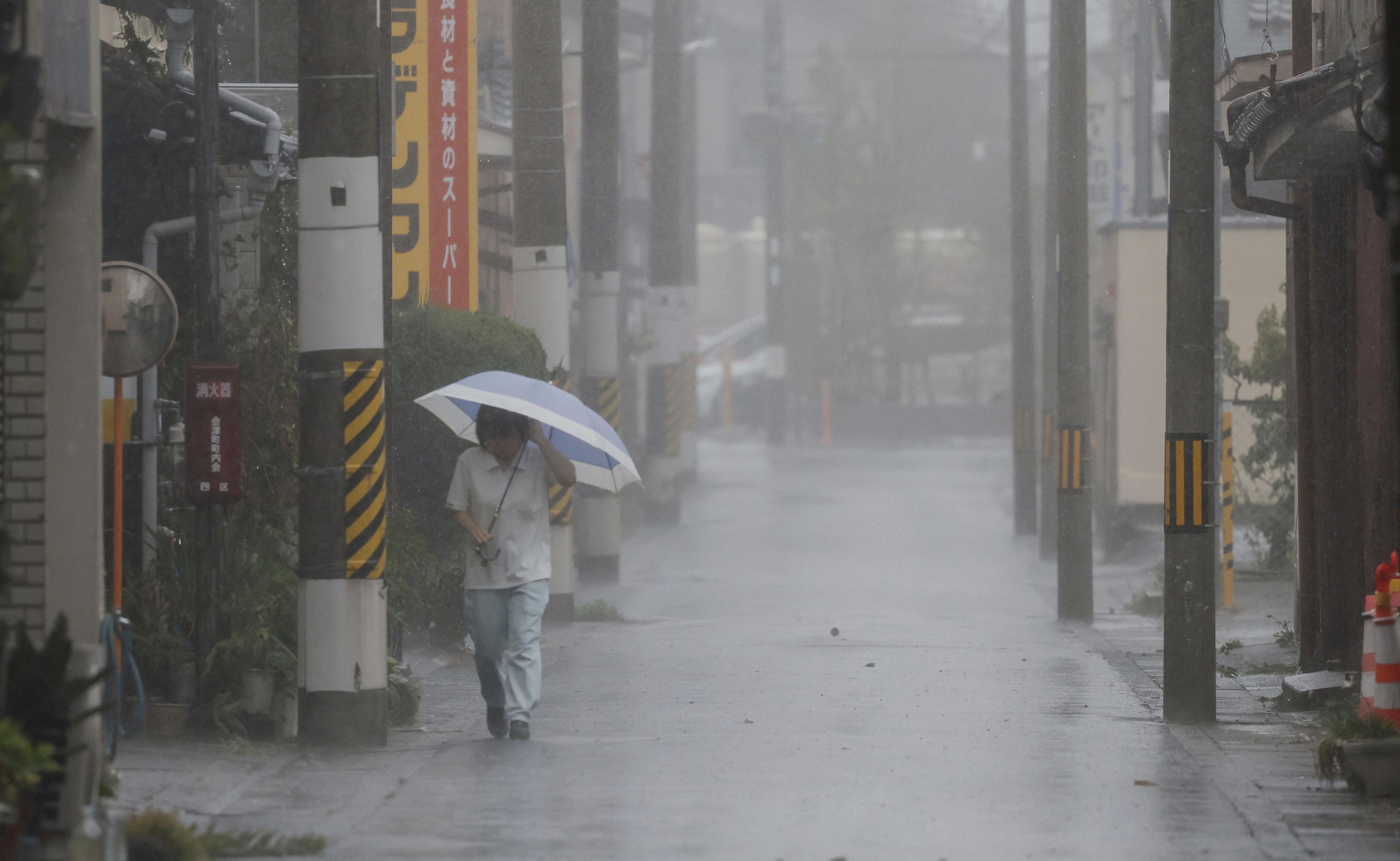 Una persona camina bajo una fuerte lluvia mientras el tifón Lan golpea la región de Tanabe, al oeste de Japón 15 de agosto 2023, en esta foto tomada por Kyodo.  Crédito obligatorio Kyodo via REUTERS