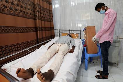 Mohamed Adawe, un ingeniero mecánico de 21 años, está de pie junto a un paciente que utiliza su respirador caseroen su casa en el distrito de Hodan de Mogadiscio, Somalia, el 6 de mayo de 2020 (REUTERS/Feisal Omar)