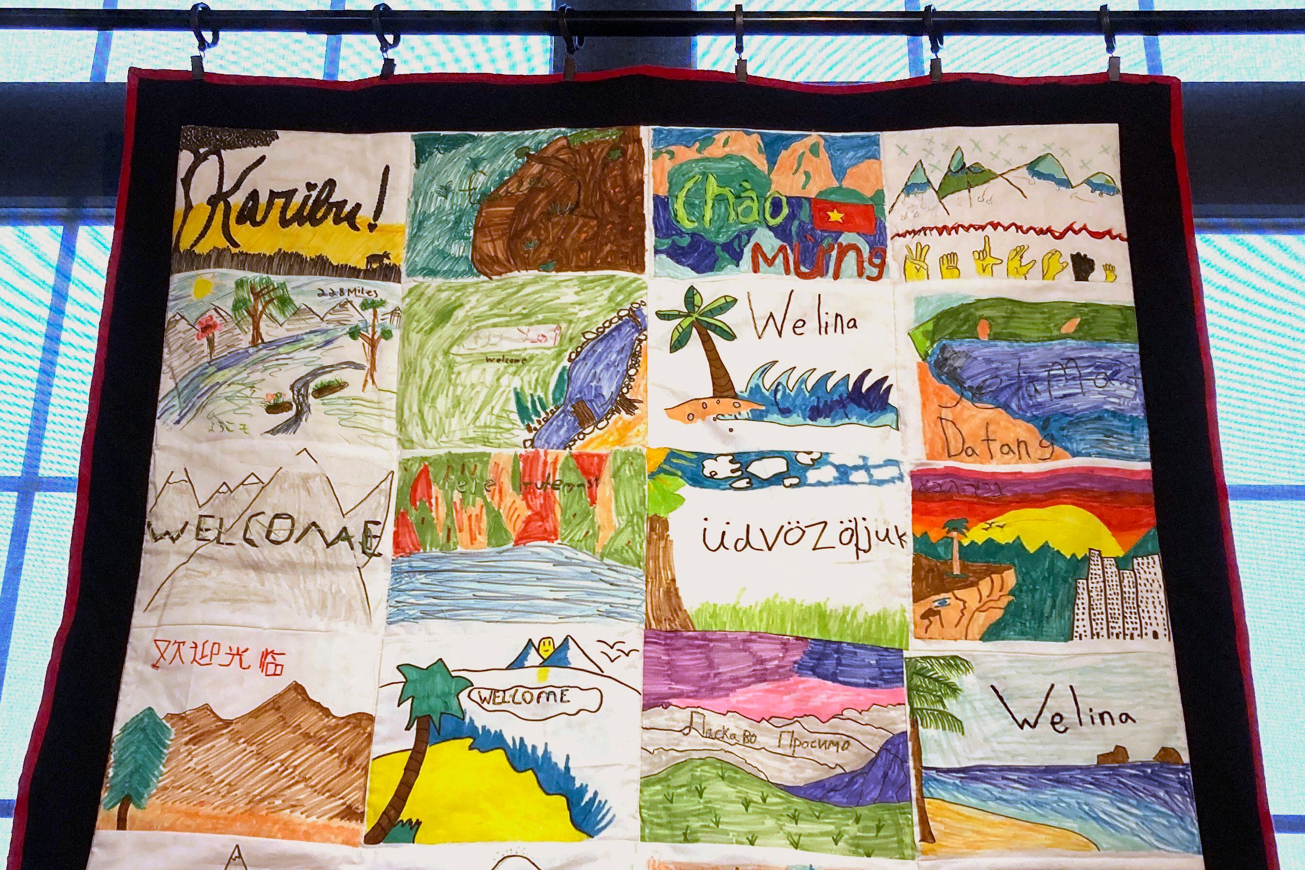 Una manta hecha a mano con la palabra "bienvenido" en muchos idiomas se ve expuesta en la muestra de Manta de Bienvenida en el Winooski Heritage Mill Museum, el 17 de febrero de 2023, en Winooski, Vermont. Las cobijas se regalaron a refugiados. (AP Foto/Lisa Rathke)