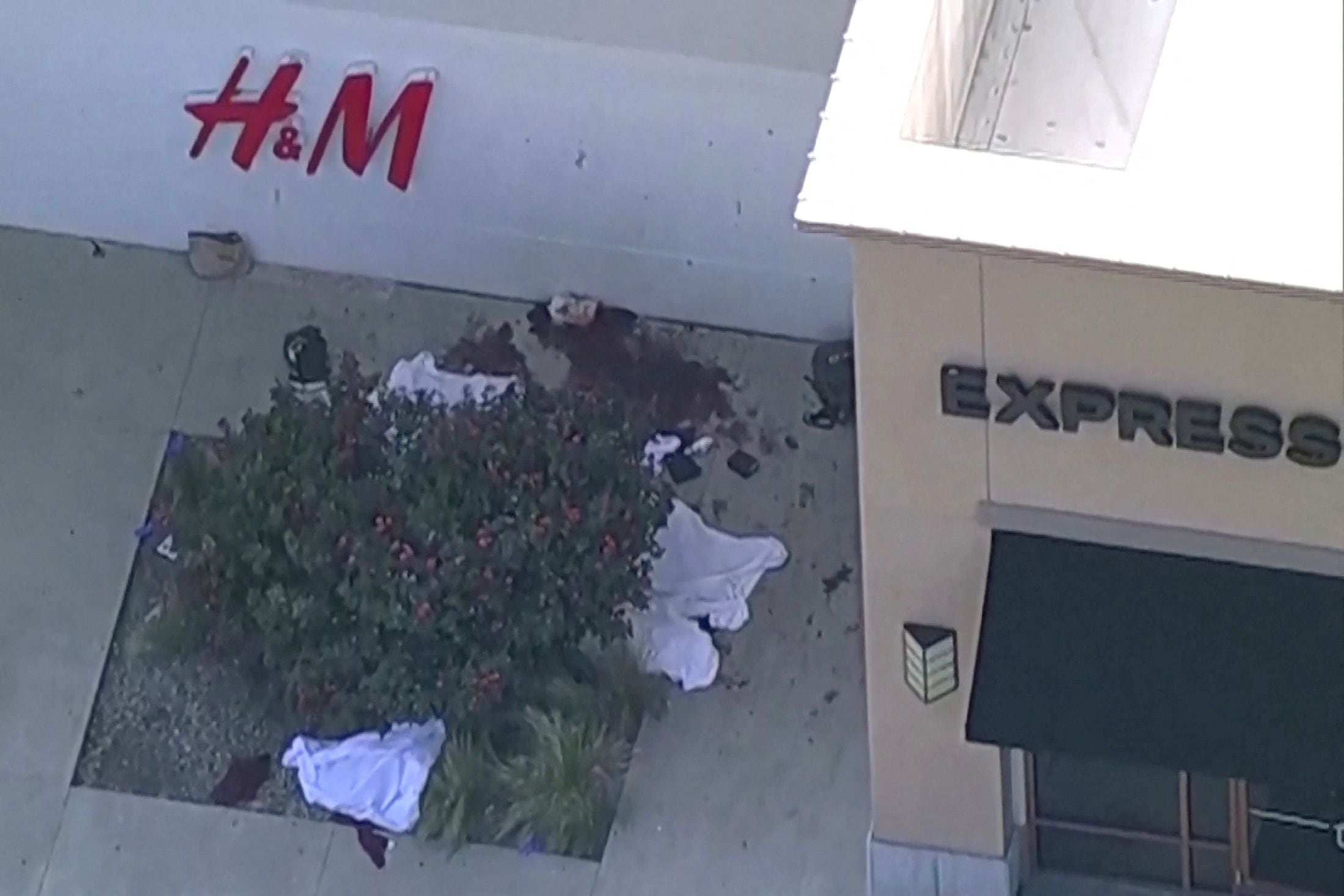 Sábanas blancas que cubrían lo que parecían ser cuerpos yacen afuera de una tienda de ropa. Afiliado de ABC WFAA a través de REUTERS