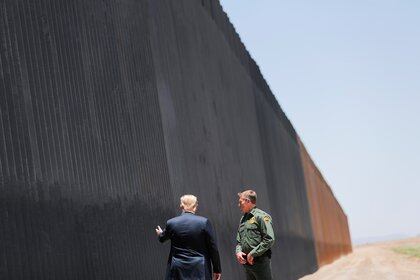 Donald Trump señala hacia el muro mientras habla con el jefe de la Patrulla Fronteriza de los Estados Unidos, Rodney Scott, durante su visita en Arizona (Foto: Reuters)