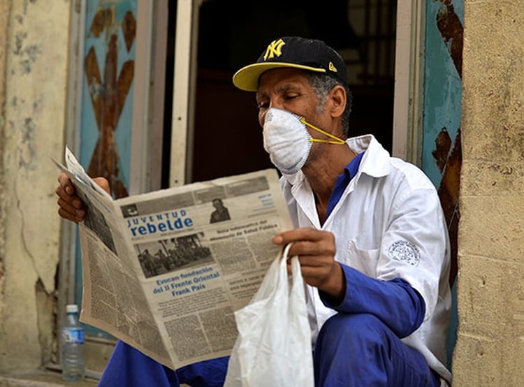 Un hombre con barbijo leyendo un diario en La Habana (Photo by Yamil LAGE / AFP)