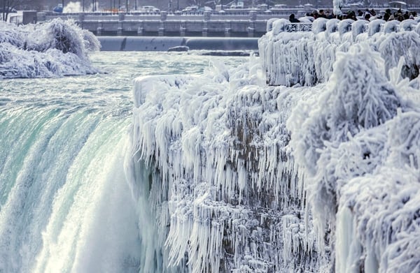 Visitors take photographs at the brink of the Horseshoe Falls in Niagara Falls, Ontario, as cold weather continues through much of the province on Friday, Dec. 29, 2017. (Aaron Lynett/The Canadian Press via AP)