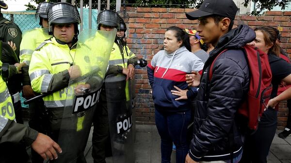 Colombianos charlan con policías que custodian el campamento de venezolanos (EFE)