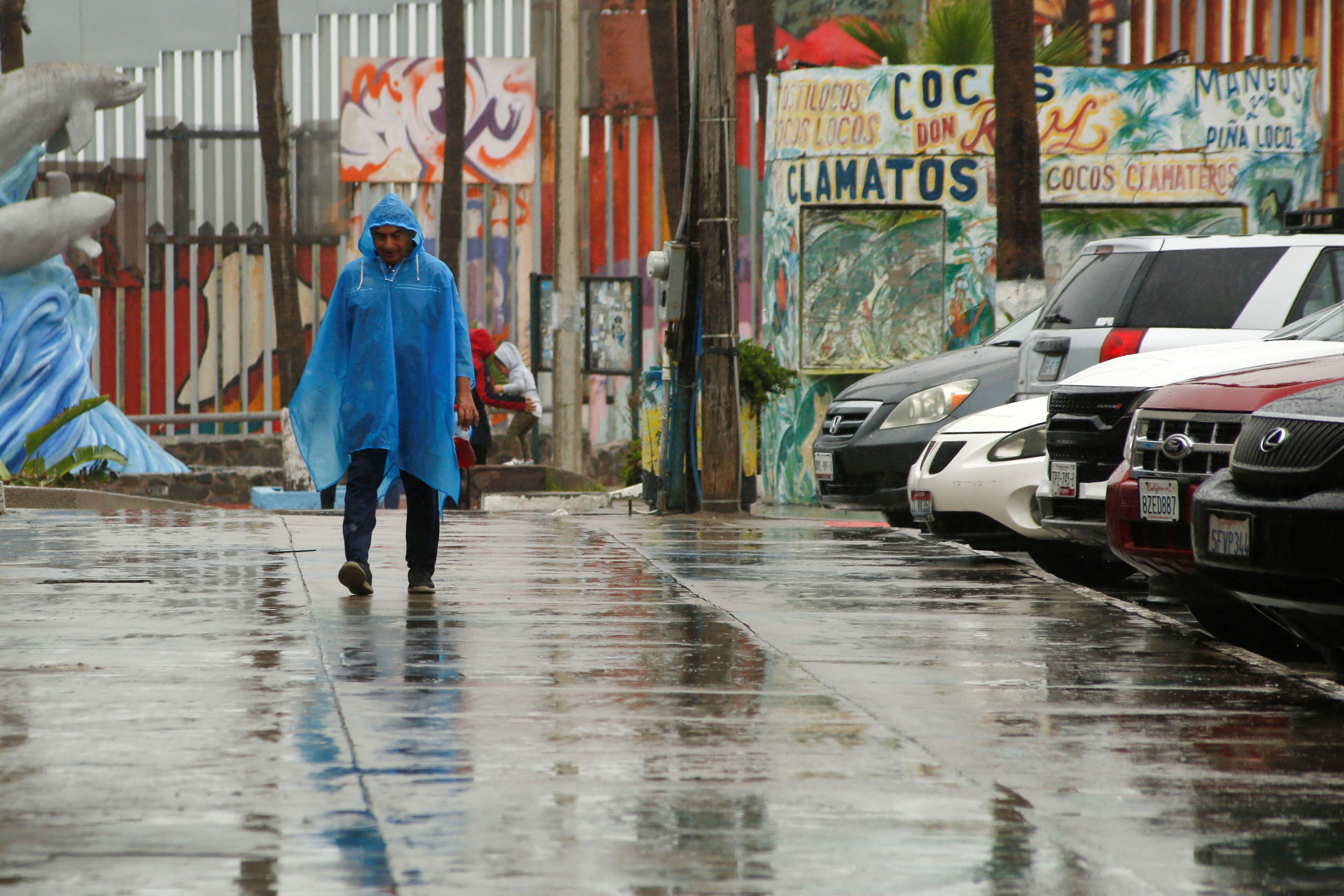 A man wearing a blue rain cover walks as Tropical Storm Hilary hits Baja California state, in Tijuana, Mexico August 20, 2023. REUTERS/Aimee Melo NO RESALES. NO ARCHIVES