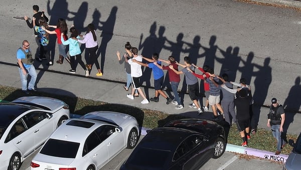 Estudiantes del colegio en Florida, víctima del último ataque, salen del edificio custodiados por la policía. (AFP)
