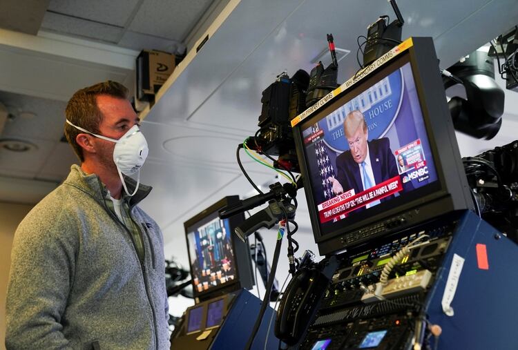 Un técnico de televisión en la parte trasera de la sala de prensa de la Casa Blanca, mientras Trump habla en la sesión informativa (REUTERS/Kevin Lamarque)