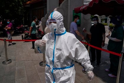 Un médico con un traje de protección es visto en las inmediaciones del hospital de Youan donde la gente hace cola para hacerse el test de coronavirus en Pekín, China. EFE/ Stringer
