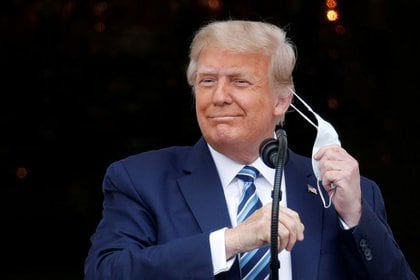 El presidente de Estados Unidos, Donald Trump, se quita la mascarilla al salir al balcón de la Casa Blanca para hablar con los partidarios reunidos en la Casa Blanca, en Washington, EEUU, 10 de octubre de 2020. REUTERS/Tom Brenner