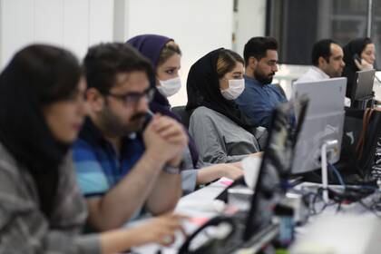 Empleados de una empresa financiera usan máscaras protectoras monitorean los precios de las acciones en Teherán, Irán, el 12 de mayo de 2020 (WANA / Agencia de Noticias de Asia Occidental /Ali Khara vía REUTERS)