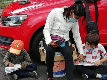 Esta mamá lleva a sus hijos a donde trabaja cuidando coches para asegurarse que comprendan bien sus actividades escolares y hagan la tarea Foto: Iztacalco Me Gusta