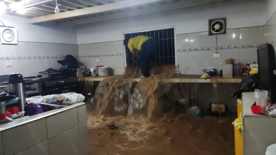 Una personas tratando de sacar el agua que ingresó a su vivienda