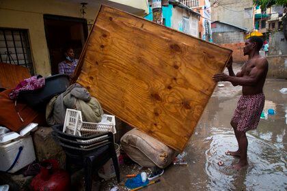 Una pareja saca algunas de sus cosas a la calle para que se sequen luego de que su casa se inundó por las fuertes lluvias provocadas por Laura en Santo Domingo (República Dominicana) (EFE)