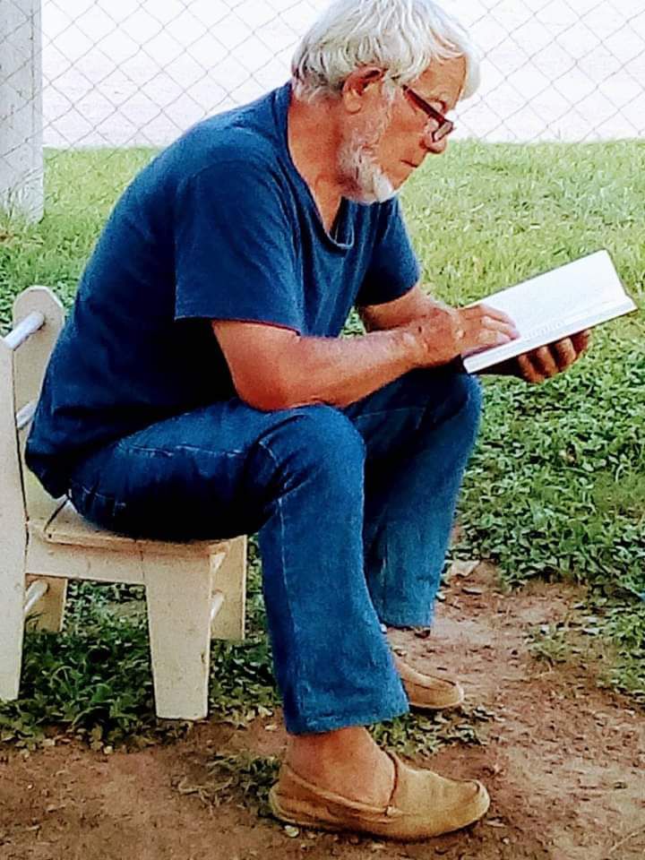 Ramón Contreras leyendo en la puerta de su casa