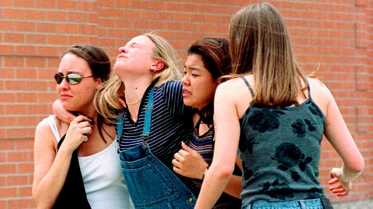 Una mujer se abraza junta a alumnas de la escuela de Columbine, cerca la biblioteca, pocos después de la masacre del 20 de abril de 1999. (AP Photo/Kevin Higley)