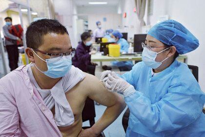 Un hombre con mascarilla para combatir los contagios de coronavirus recibe una dosis de la vacuna de Sinovac contra el COVID-19 en un centro de salud en Hangzhou, en la provincia oriental china de Zhejiang, el lunes 15 de marzo de 2021. (Chinatopix Via AP)