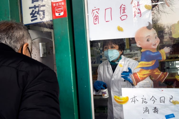 Un hombre compra medicina en una farmacia en Beijing a través de una ventana, una precaución tomado para combatir el coronavirus el domingo, 9 de febrero 2020. (Giulia Marchi/The New York Times)