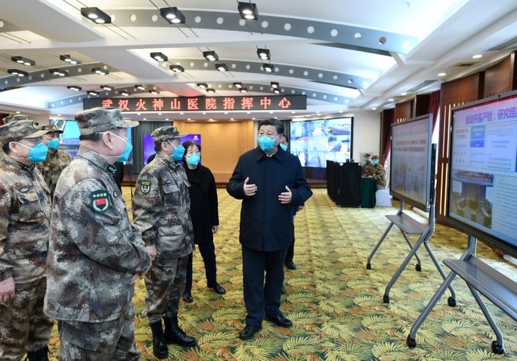 El presidente de China, Xi Jinping, habla con un equipo médico durante su visita a pacientes de coronavirus en Wuhan el 10 de marzo de 2020 (Xie Huanchi/Xinhua vía Reuters)