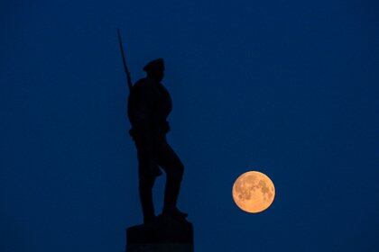 La luna llena se muestra detrás del Monumento a los Héroes de la Primera Guerra Mundial en la colina Poklonnaya en Moscú a principios del 26 de abril de 2021. (Foto de Kirill KUDRYAVTSEV / AFP)