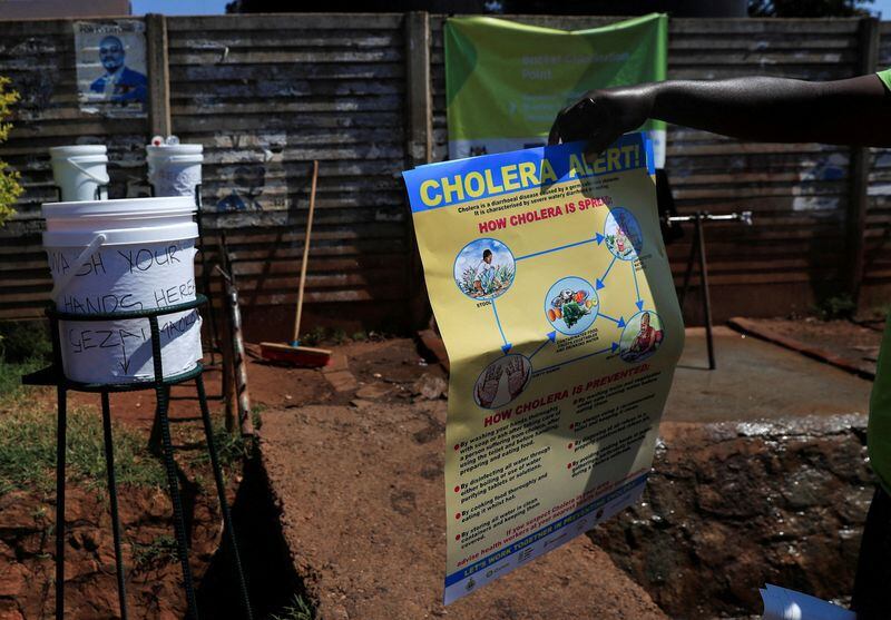 Un hombre sostiene información en un cartel sobre el cólera afuera de una tienda de campaña en un policlínico en Harare, Zimbabue. ( REUTERS/Philimon Bulawayo)