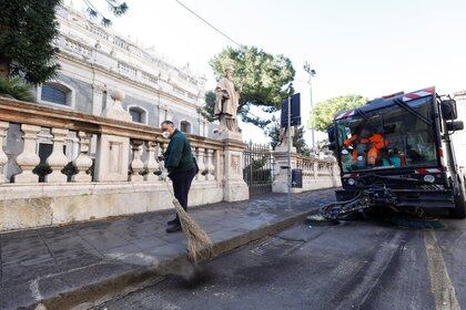 Trabajadores limpian una calle después de una impresionante erupción volcánica del Monte Etna en Catania, Italia, el 17 de febrero de 2021. REUTERS / Antonio Parrinello