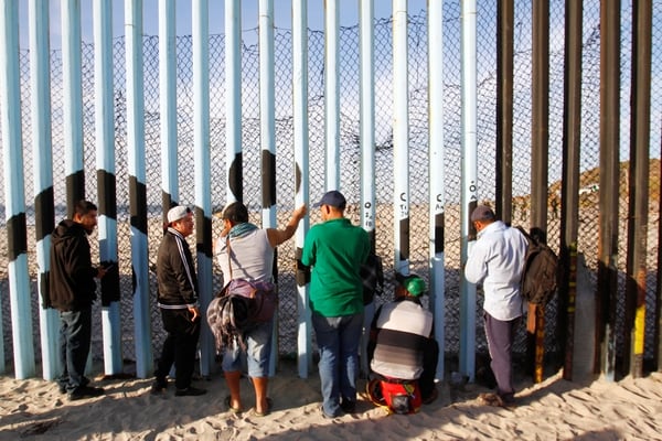 Miembros de la caravana migrante que intenta llegar a EEUU observan a través del vallado fronterizo en Tijuana, Mexico (REUTERS/Jorge Duenes)