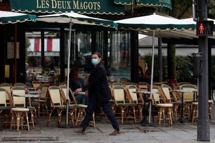 A woman wearing a protective face mask walks past the cafe and restaurant Les Deux Magots in Paris, during the announcement of new Covid restrictions by Paris authorities as the coronavirus disease (COVID-19) outbreak continues in France, October 5, 2020. REUTERS/Gonzalo Fuentes